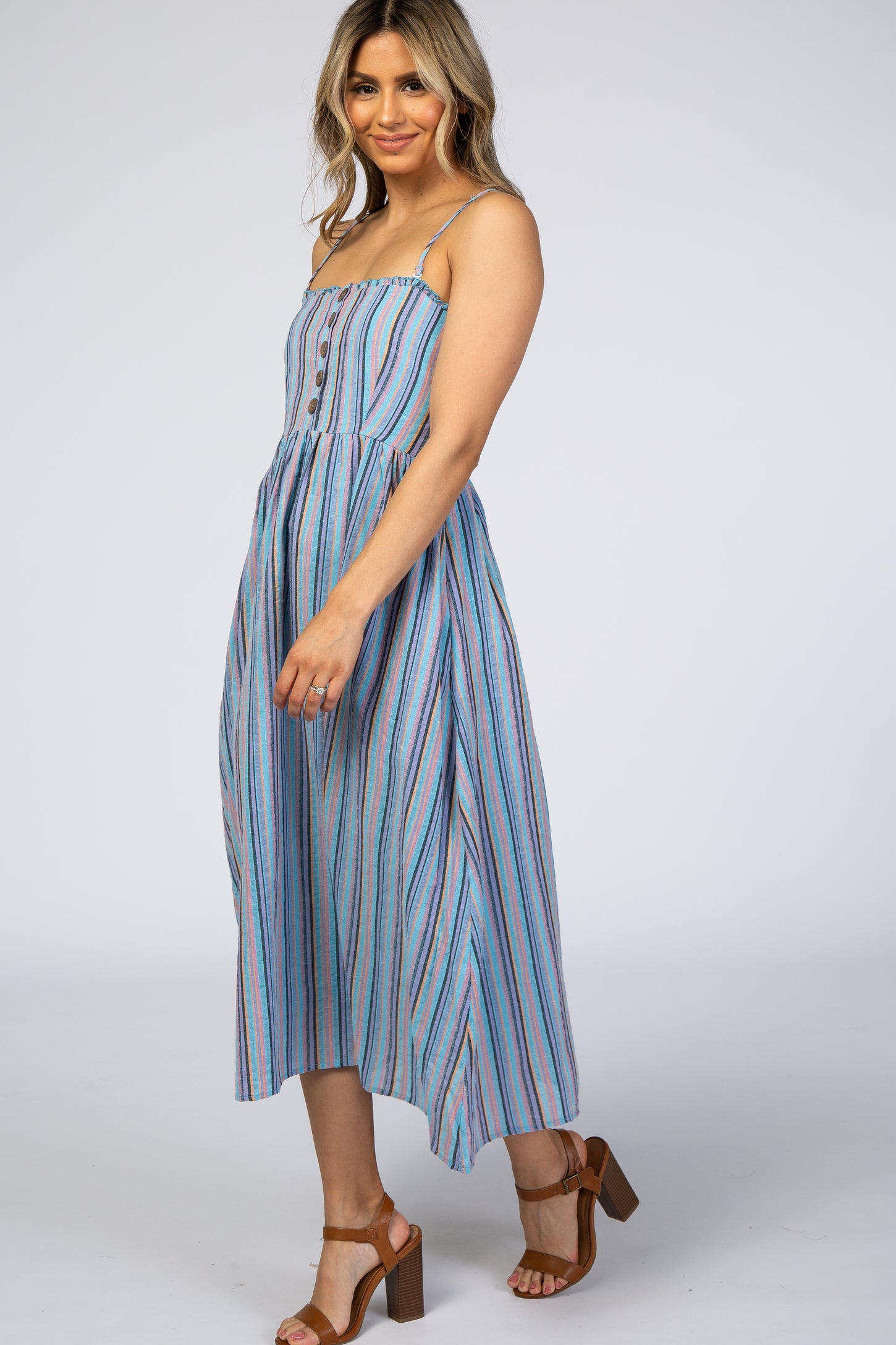 woman wearing a blue striped midi dress with buttons and spaghetti straps, standing in a side pose