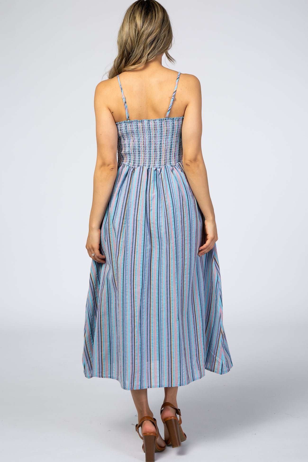 woman wearing a back view of a light blue striped maxi dress with spaghetti straps and a smocked bodice