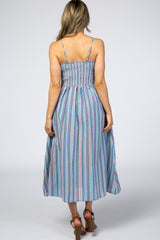 woman wearing a back view of a light blue striped maxi dress with spaghetti straps and a smocked bodice