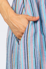 woman's hand in the pocket of a multicolored striped dress with blue, pink, and orange tones