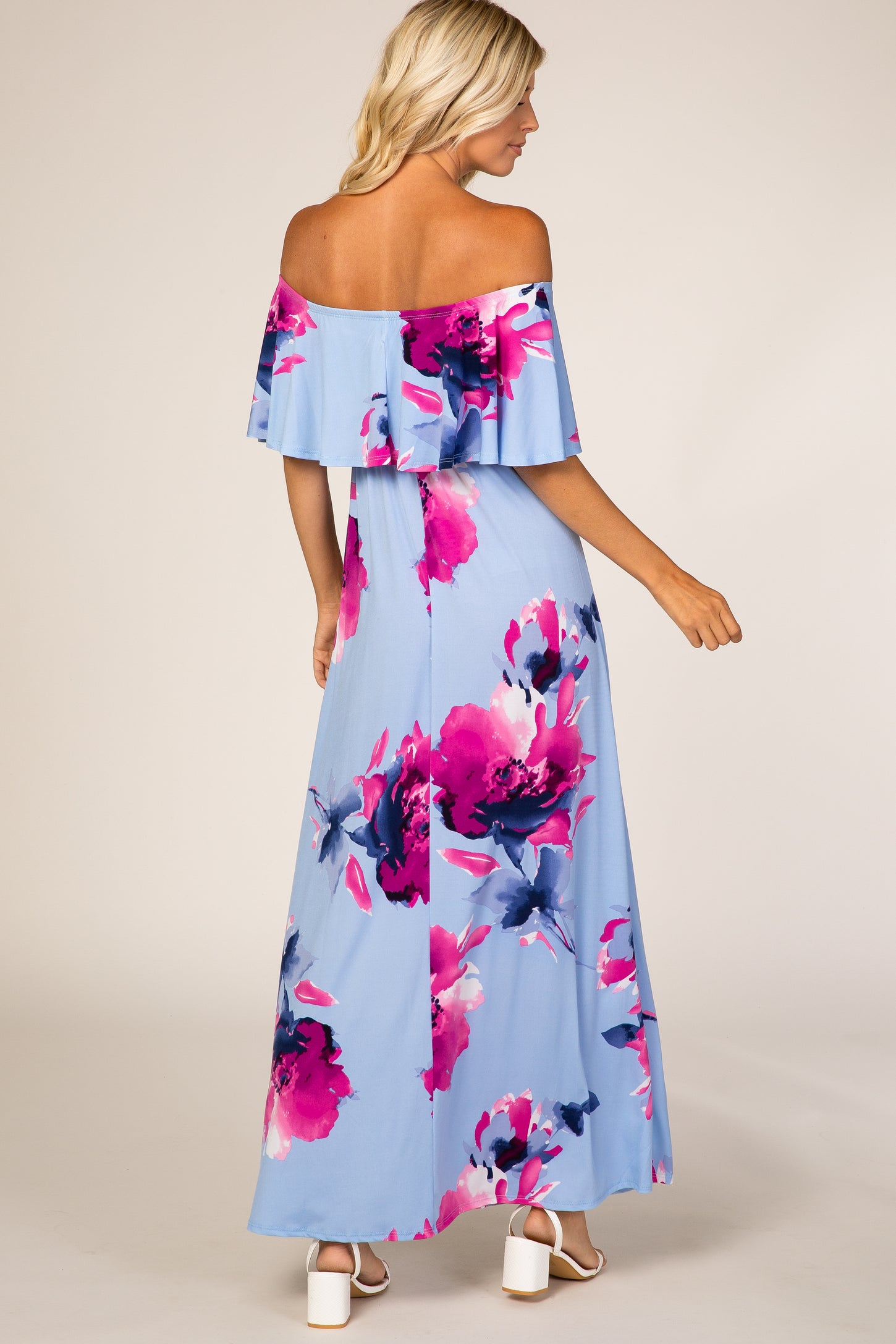 Woman wearing light blue off-the-shoulder floral maxi dress with pink flowers and white block heels