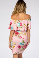Back view of a woman wearing a pink floral off-the-shoulder maternity dress with a ruffled neckline.