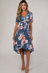 woman wearing a blue floral maternity wrap dress with short sleeves and a high-low hemline