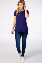 woman wearing a purple short sleeve maternity top and blue skinny jeans with a baby bump visible