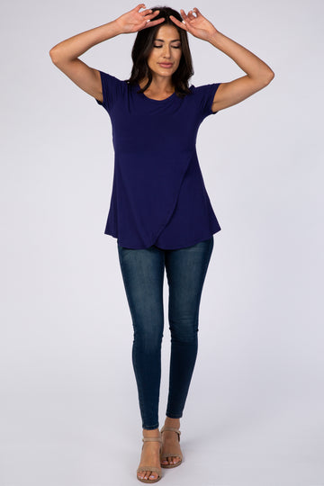 woman wearing a navy blue short sleeve top with an asymmetrical hem and fitted jeans