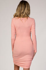 woman wearing a blush pink long sleeve ribbed maternity dress with ruching on the sides