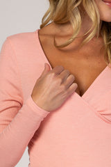 woman wearing a light pink textured maternity top with a v-neckline and long sleeves