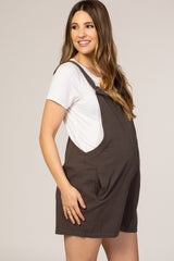 pregnant woman wearing charcoal grey maternity overalls and a white t-shirt against a neutral background