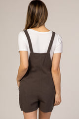 Back view of a woman wearing dark brown overalls over a white short-sleeve t-shirt