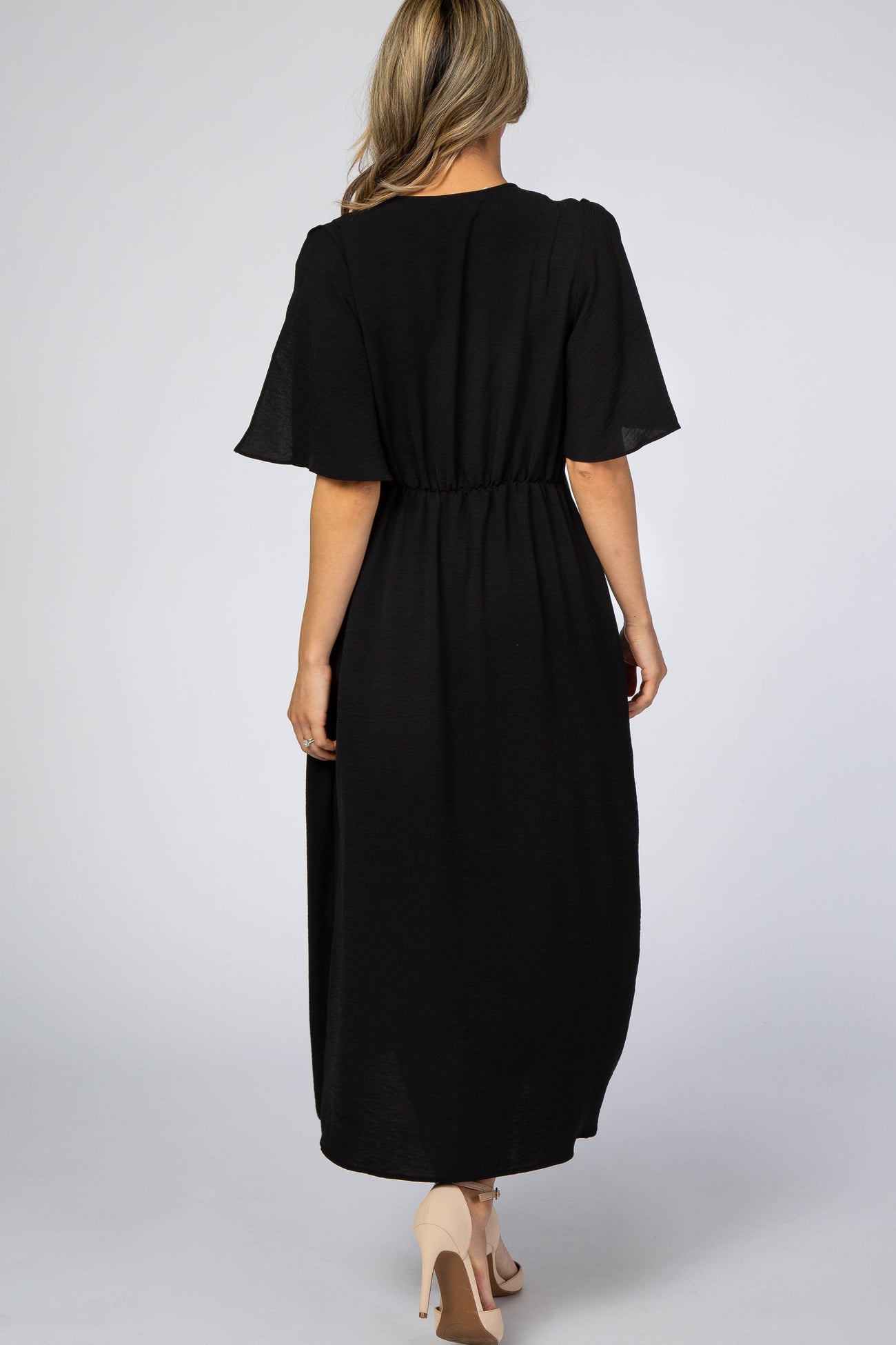 woman wearing a black maxi dress with short flutter sleeves and elastic waist, shown from the back