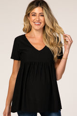 woman wearing a black short sleeve maternity top with a v-neck and a gathered waist, showing her baby bump