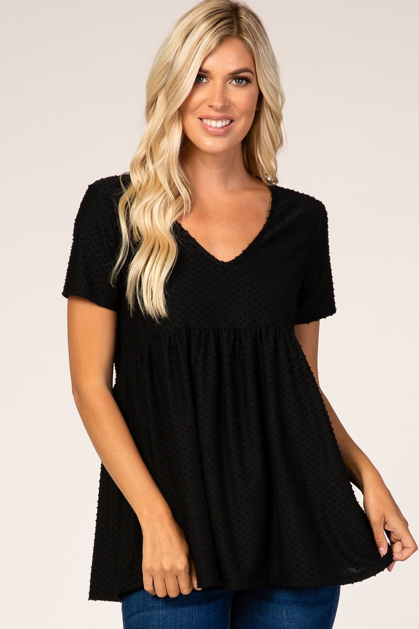 woman wearing a black short sleeve peplum top with a v-neck and textured fabric