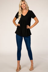 woman wearing a black short sleeve v-neck top with a peplum hem and blue skinny jeans