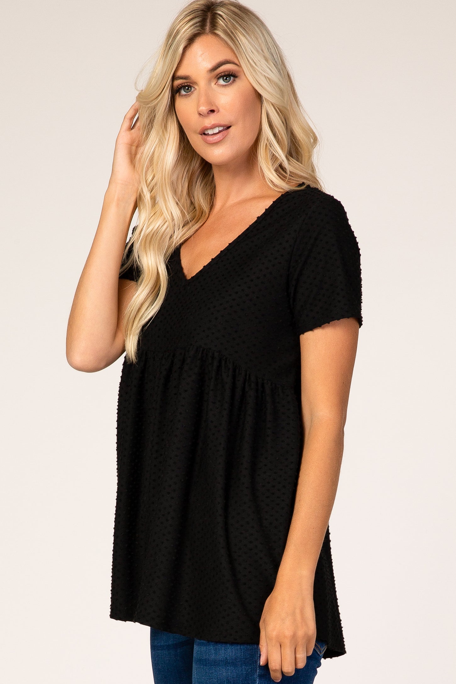 woman wearing a black short sleeve v-neck top with textured detailing and a relaxed fit