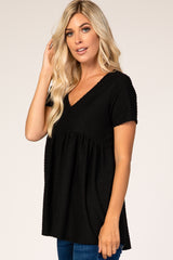 woman wearing a black short sleeve v-neck top with textured detailing and a relaxed fit