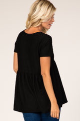 woman wearing a black short sleeve peplum top with textured fabric and a relaxed fit, shown from the back