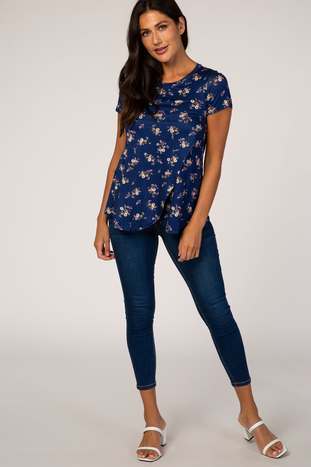 woman wearing a navy blue floral short sleeve maternity top and dark wash skinny jeans
