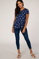 woman wearing a navy blue floral short sleeve maternity top and dark wash skinny jeans