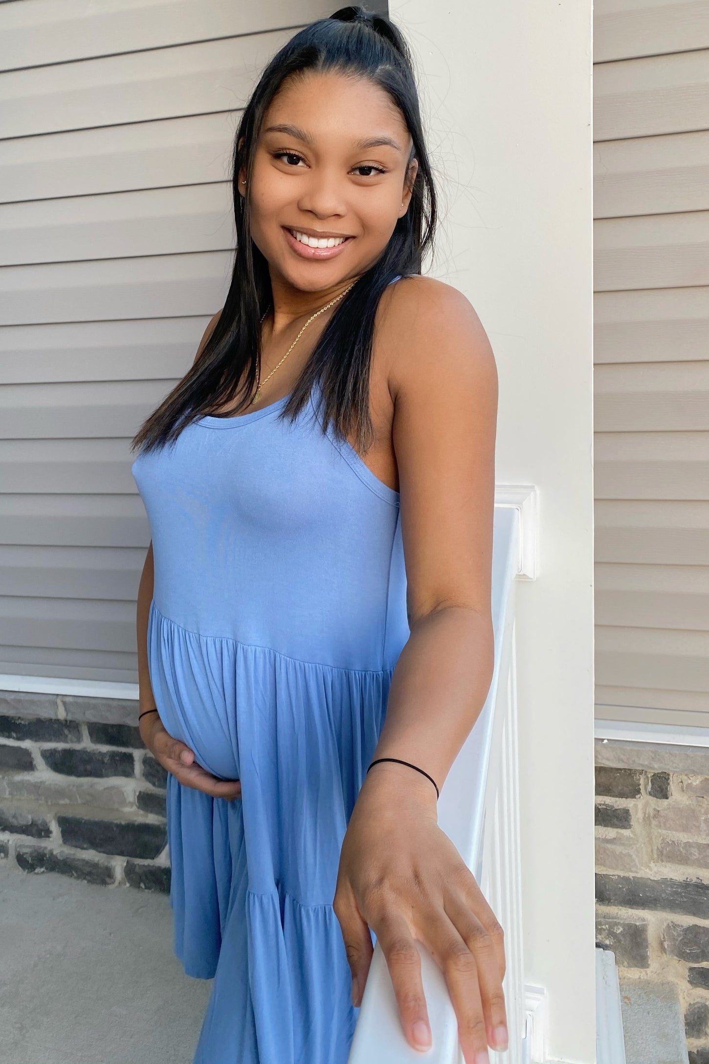 woman wearing a light blue maternity dress and holding her baby bump