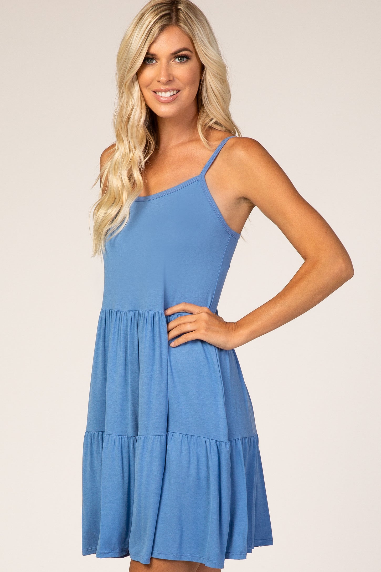 woman wearing a light blue sleeveless tiered dress with a fitted bodice and flared skirt