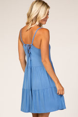 woman wearing a light blue sleeveless tiered sundress with a tie-back detail