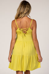 back view of woman wearing yellow tiered maternity dress with lace up back detail