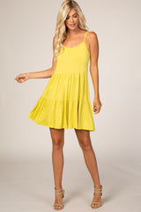 woman wearing a bright yellow spaghetti strap sundress with a flared skirt and tiered design