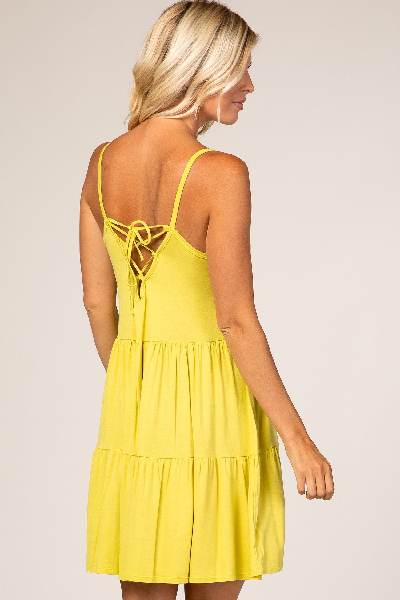 woman wearing a bright yellow tiered sundress with a tie-back detail