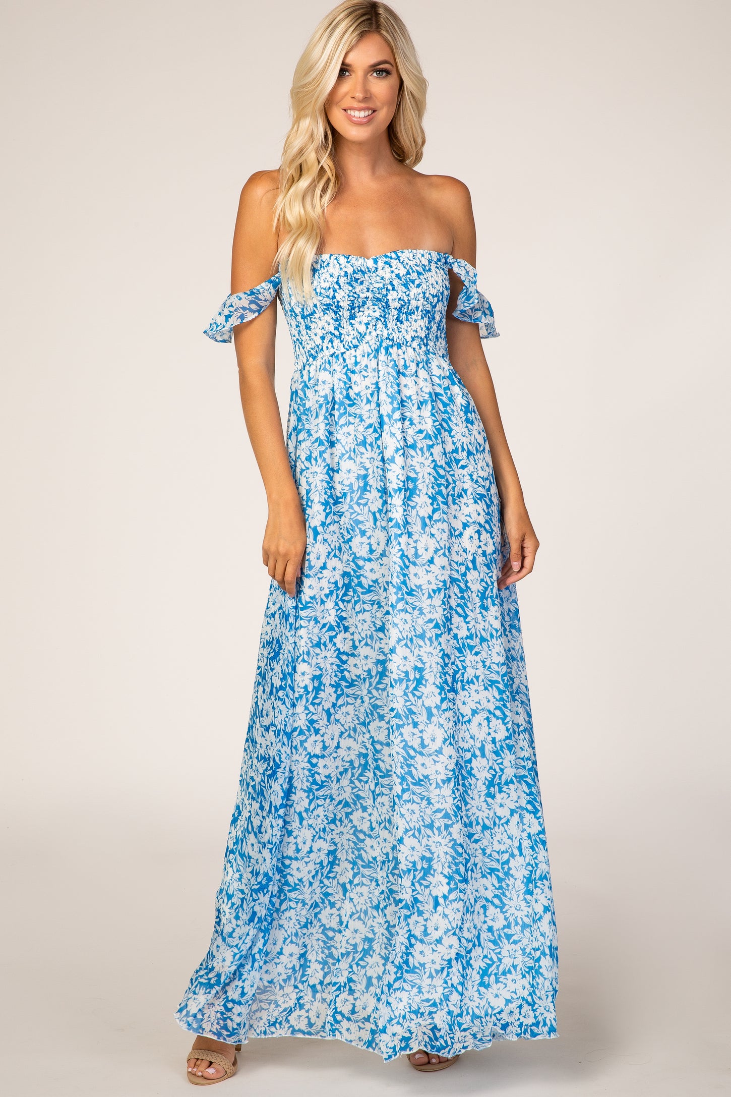 woman wearing a blue floral off-shoulder maxi dress with ruffled sleeves and a smocked bodice