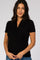 woman wearing a black short sleeve wrap top, smiling and posing with her hands on her waist