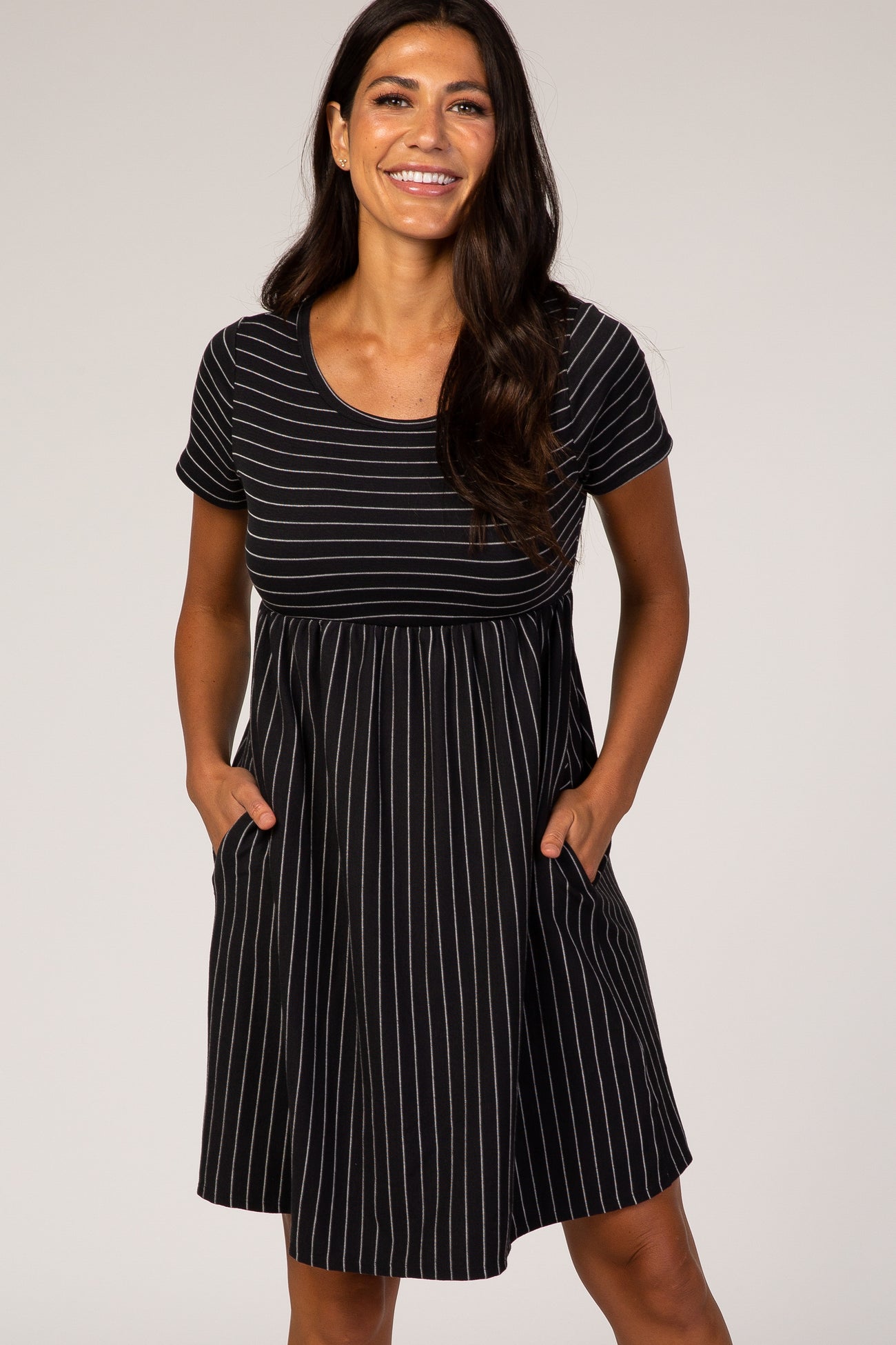 woman wearing a black and white striped short sleeve dress with pockets and a fitted bodice