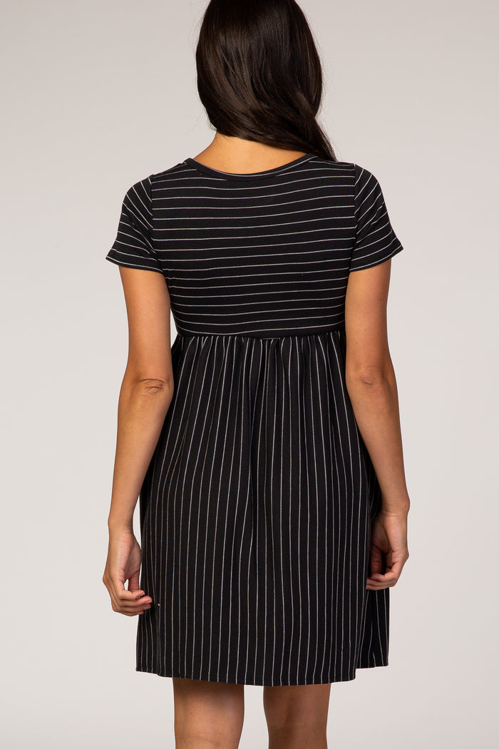 woman wearing a black and white striped short sleeve dress with a gathered waist and a flared skirt from the back