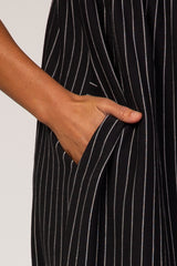 close-up of a woman's hand in the pocket of a black and white striped dress