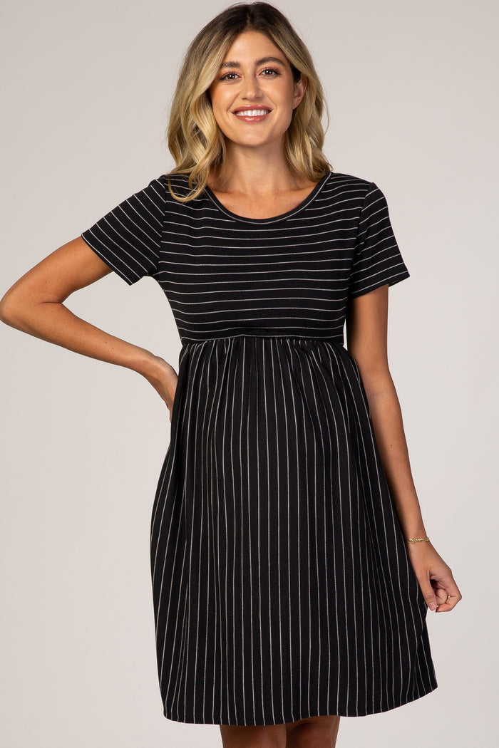 woman wearing a black and white striped maternity dress with a fitted top and flowy skirt, highlighting her baby bump