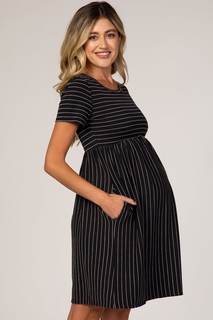 woman wearing a black and white striped maternity dress with short sleeves and pockets, showing her baby bump