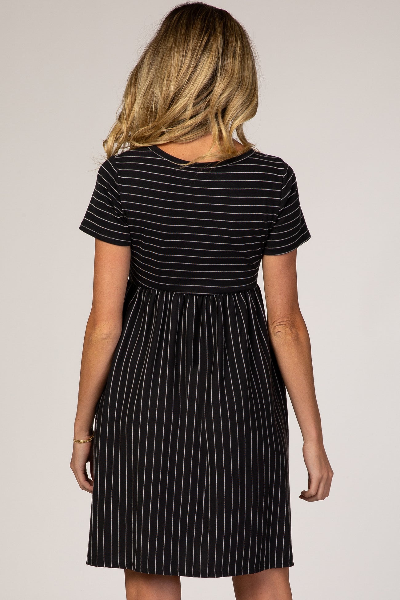 woman wearing a black and white striped maternity dress with short sleeves and a fitted waistline