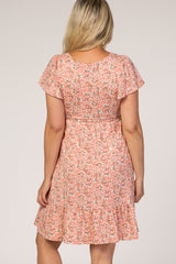 woman wearing a pink floral maternity dress with short flutter sleeves and a ruffled hem