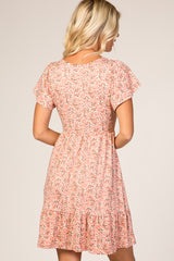 woman wearing a pink floral short-sleeve dress with a tiered ruffle hem and a fitted waist, viewed from the back