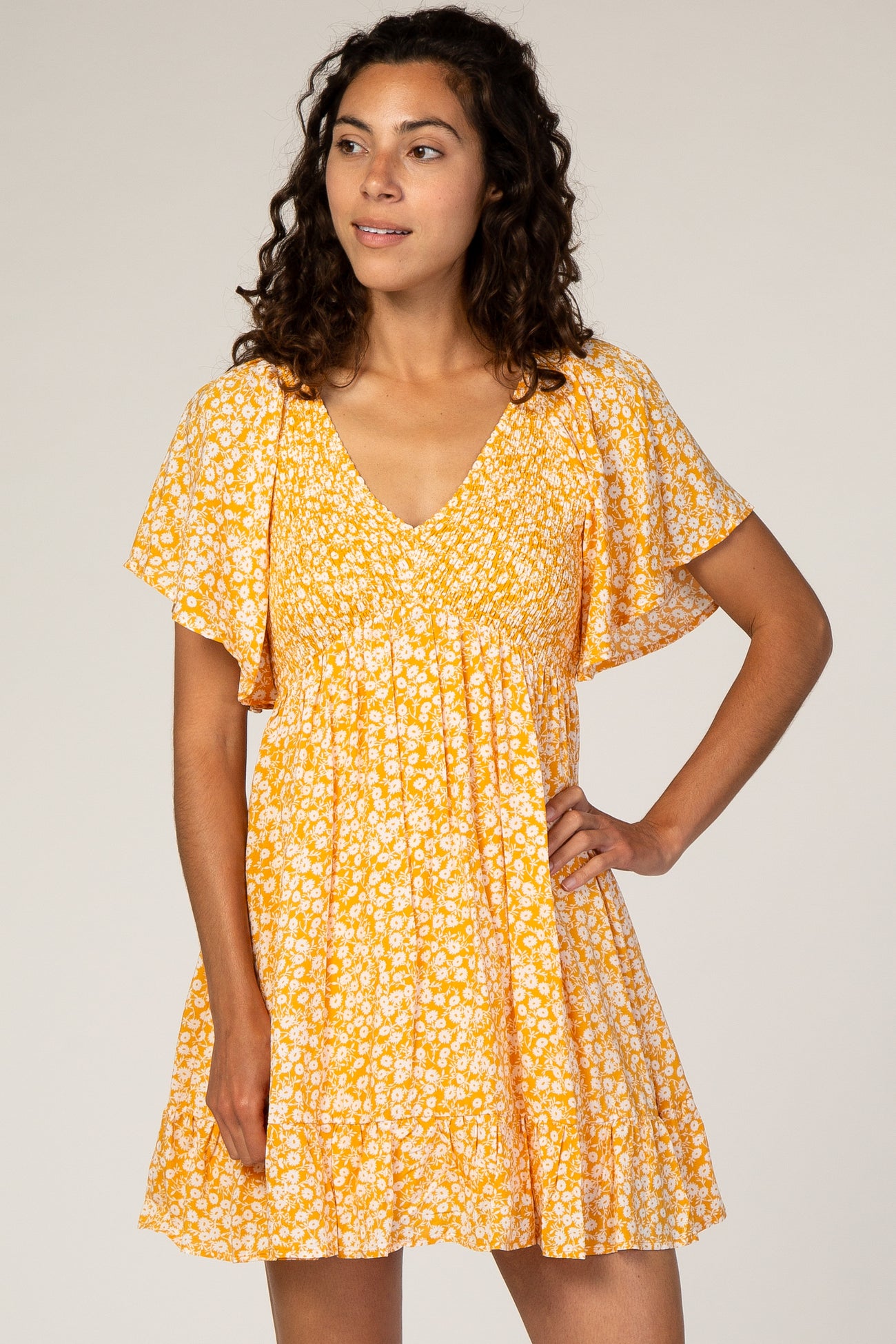 woman wearing a yellow floral print short dress with v-neck and flutter sleeves