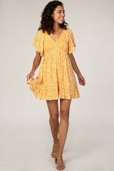 woman wearing a yellow short sleeve floral dress with a v-neck and flared skirt, smiling and walking