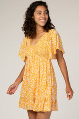 woman wearing a yellow floral short dress with a v-neckline and flutter sleeves