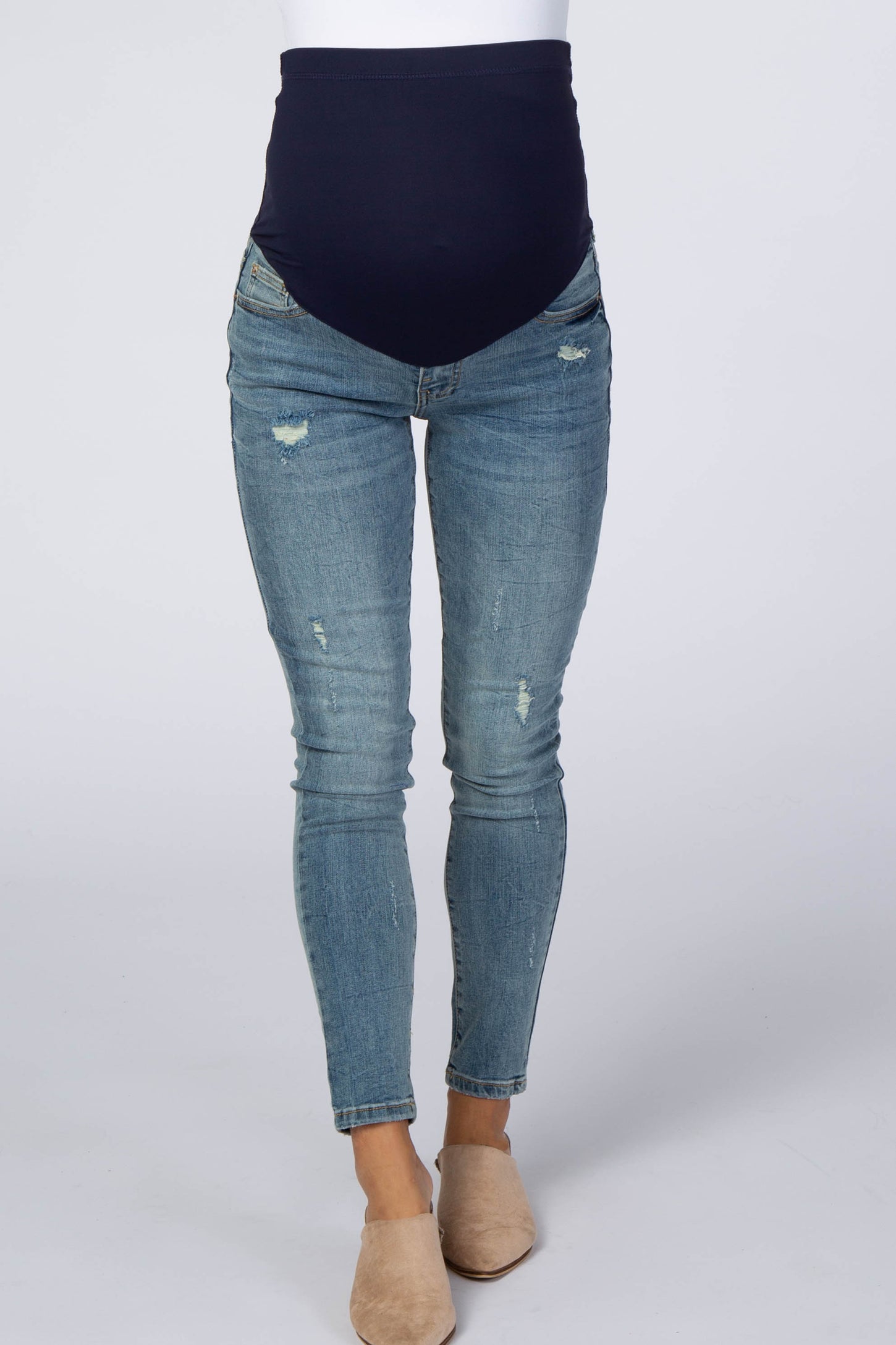 woman wearing a pair of distressed maternity skinny jeans with a navy blue over-the-bump waistband