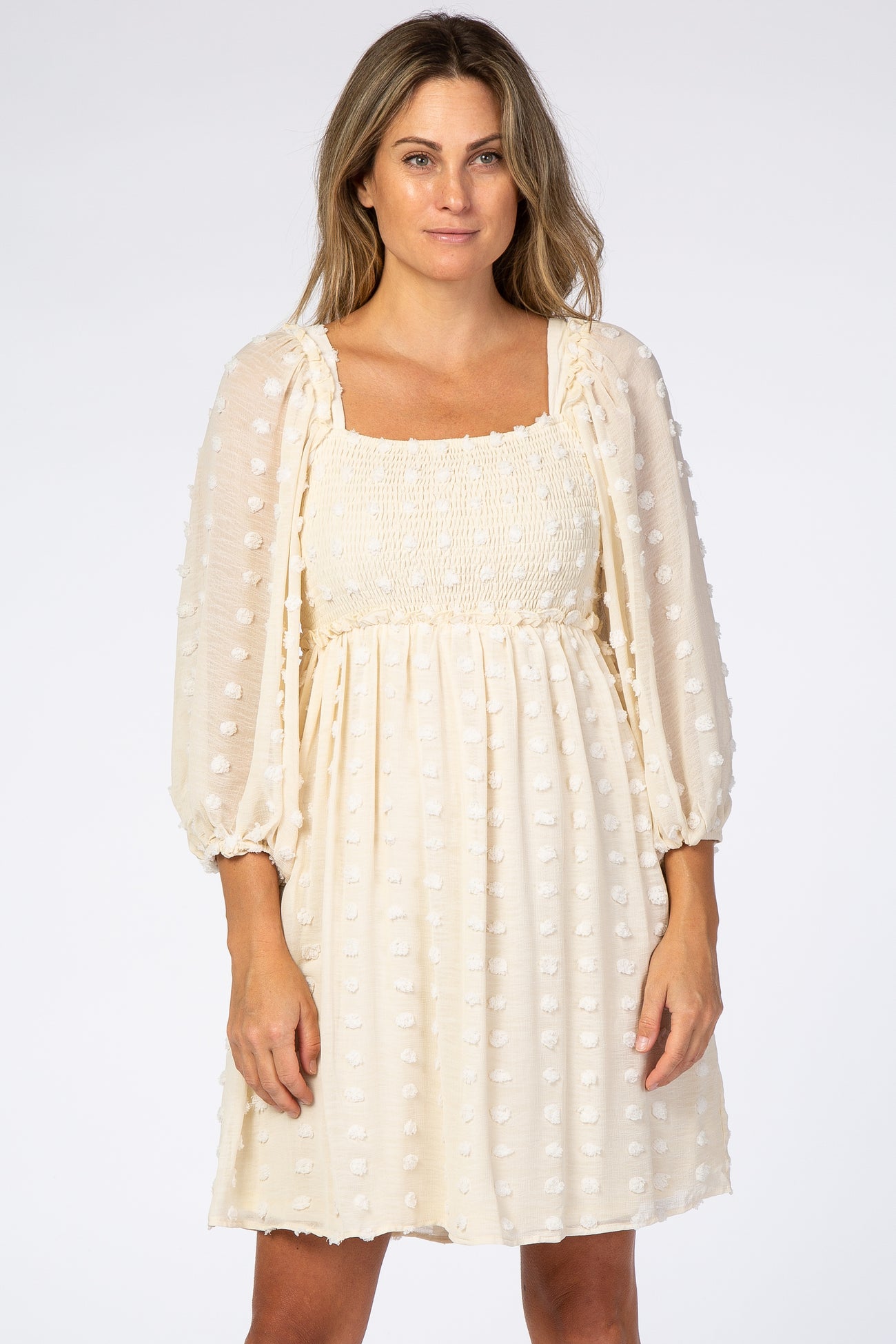 woman wearing cream swiss dot maternity dress with smocked bodice and long puff sleeves