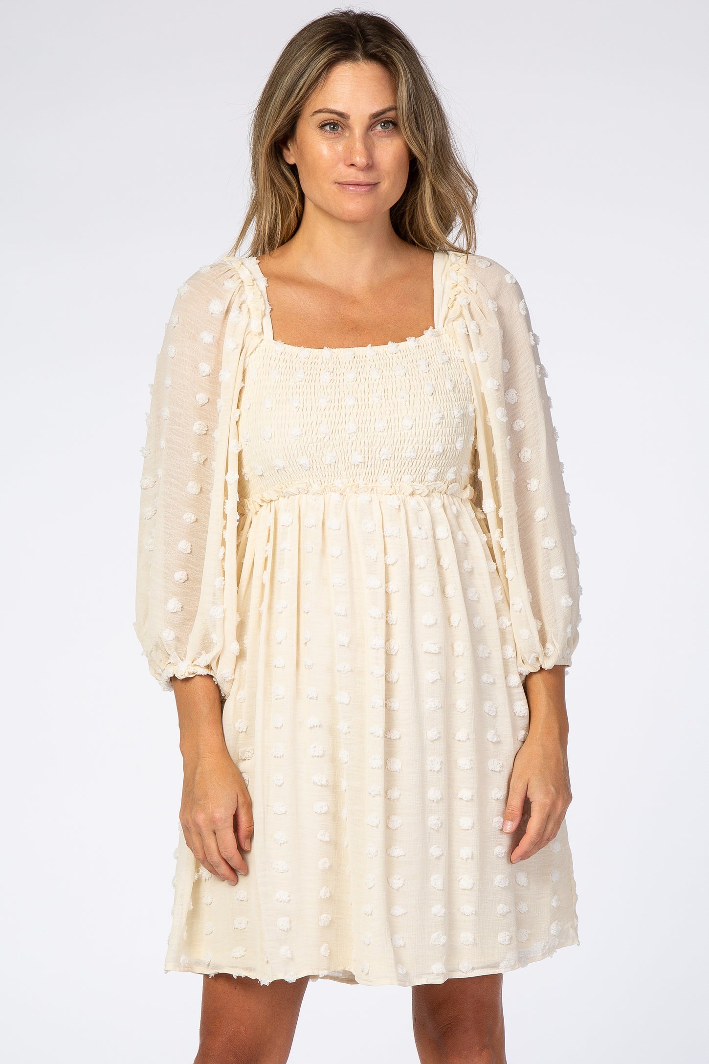 woman wearing cream swiss dot maternity dress with smocked bodice and long puff sleeves