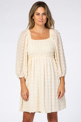 woman wearing cream swiss dot maternity dress with smocked bodice and long puff sleeves