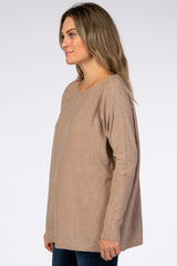 woman wearing a beige long sleeve oversized top with a relaxed fit and a scoop neckline