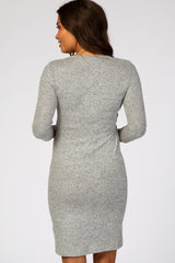 woman wearing a fitted gray maternity dress with three-quarter sleeves, showing her back and style details