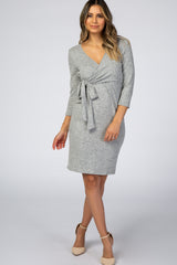 woman wearing a light grey knit wrap dress with three-quarter sleeves and a tied waist detail