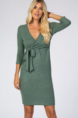 woman wearing a green wrap dress with three-quarter sleeves and a tie at the waist