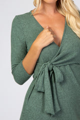 woman wearing a green wrap dress with three-quarter sleeves and a tied waist detail